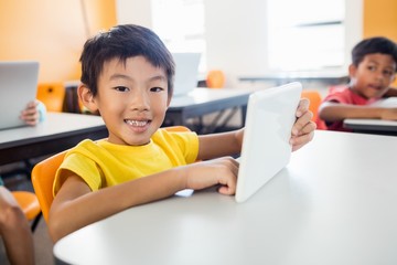 Happy boy posing with tablet at desk