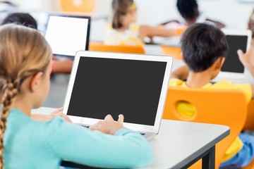 Rear view of pupils working in classroom with laptop