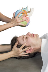 Physiotherapist doing a cranial sacral therapy to a man patient.