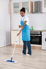 Female Janitor Mopping Floor In Kitchen