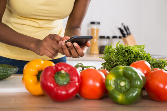Close-up Of A Woman Using Mobile Phone In Kitchen