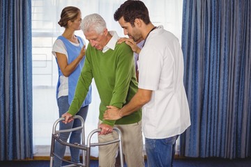 Nurse helping seniors walking with a walker