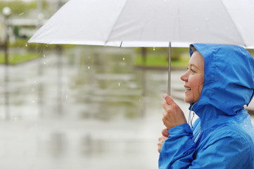 Portrait of smiling woman under umbrella in rain.