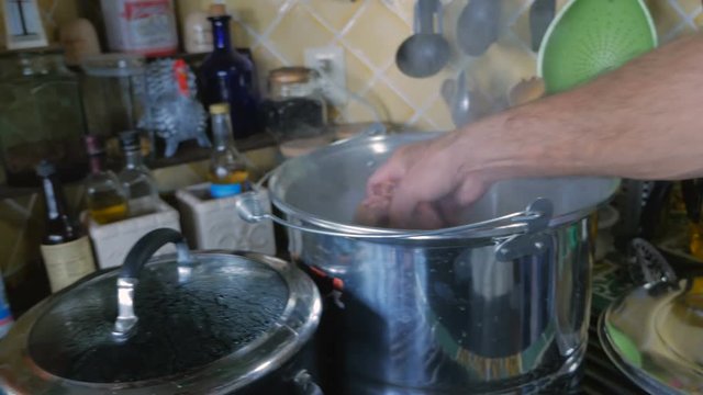 A man takes raw chicken livers out of a bag and places them in a pot.