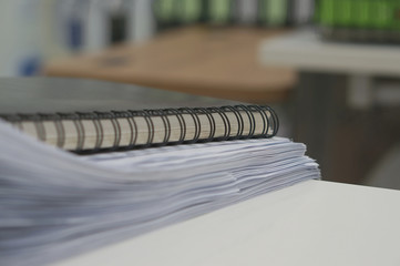 Black notebook and stack of white document