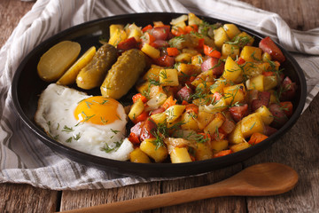 Finnish food pyttipannu: fried potatoes with sausages, eggs and pickled . horizontal
