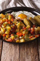 Scandinavian fried potatoes with sausages, eggs and pickled close-up. vertical
