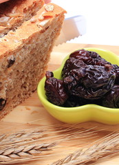 Slicing fresh bread, dried plums and ears of wheat