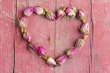 Rose flowers in heart shape on old wooden background