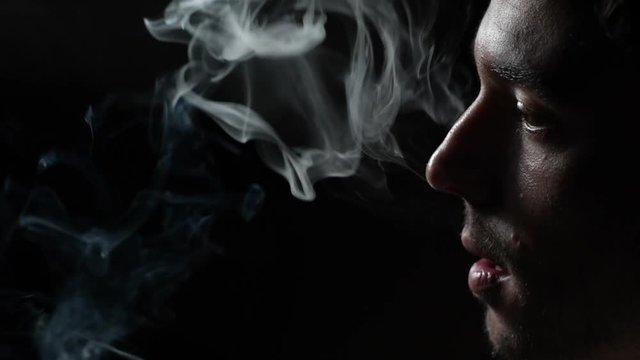Man smoking cigarette on black background