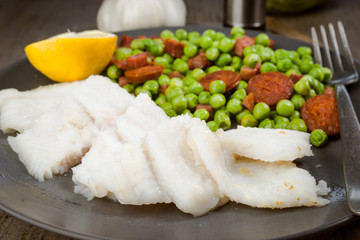 plate of grilled fish and cooked with ham and chorizo peas in ol