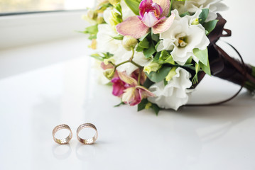 bridal bouquet on white background and two gold rings. Wedding card