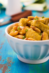 Chicken with white beans in a curry sauce on a blue wooden board