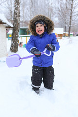 Happy 3 years toddler with shovel in winter outdoors