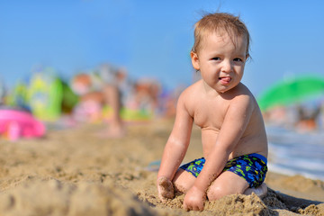 Baby playing with toys on the sandy beach near the sea.
