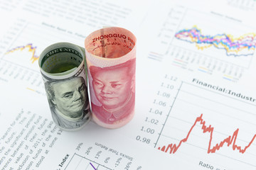 Rolled up scrolls of US dollar bill and Chinese Yuan with image / portrait of President Mao Zedong...