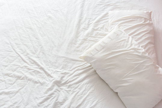 Top View Of An Untidy / Unmade Bed With White Crumpled Bed Sheet And Two Messy Pillows In A Hotel Room. An Accommodations That Is Not Neatly Arranged For A New Guest / Customer / Visitor To Sleep In.