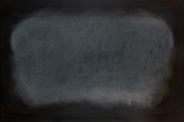 Close up view of a black dirty chalkboard without a wooden frame. Chalk on the blackboard has been...