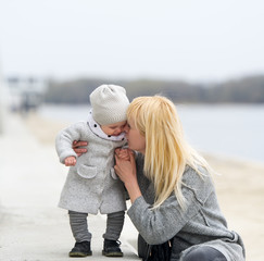 Mother gently embraces and kisses the little daughter.