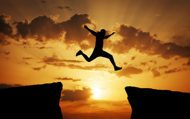 Man jumping across the gap from one rock to cling to the other.