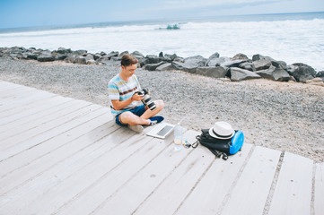 handsome young guy the photographer working with a laptop on the