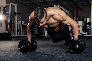 Gym man push-up strength pushup exercise with dumbbell