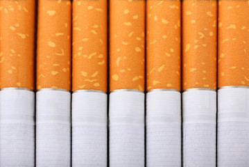 Cigarette with an orange filter lie close to each other close up