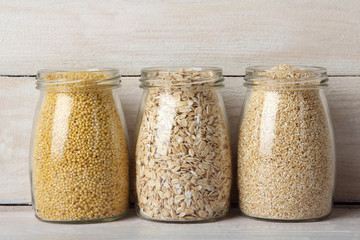 various cereals in glass jars  on wooden background