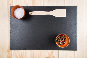 spices and a wooden spatula on a blackboard, a top view