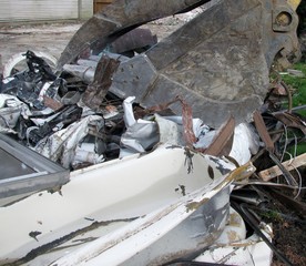 Close-up of excavator bucket loading metal parts from house demolition site