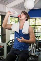 Man drinking water and listening music at spinning class