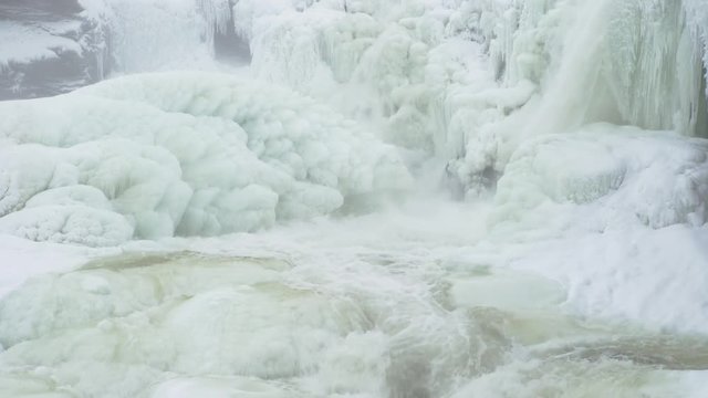 Water pours over icicles at the frozen waterfall Ristafallet in Jamtland in northern Sweden