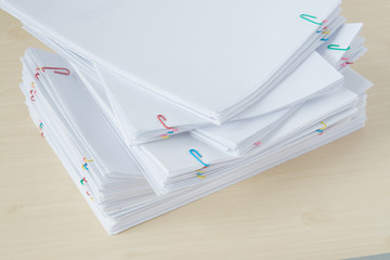 Pile of overload paperwork and reports with colorful paper clip