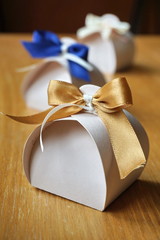 Small gift box made of paper with a colorful ribbon topnot atop on a wooden background  