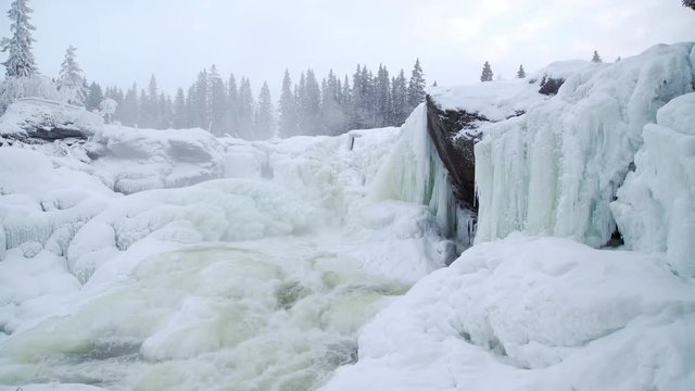 Water pours over icicles at the frozen waterfall Ristafallet in Jamtland in northern Sweden