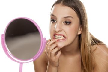 Fototapeta premium young woman checking her teeth in the mirror