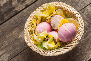 Easter eggs in nest on color wooden background