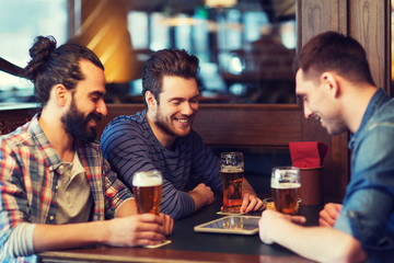 male friends with tablet pc drinking beer at bar