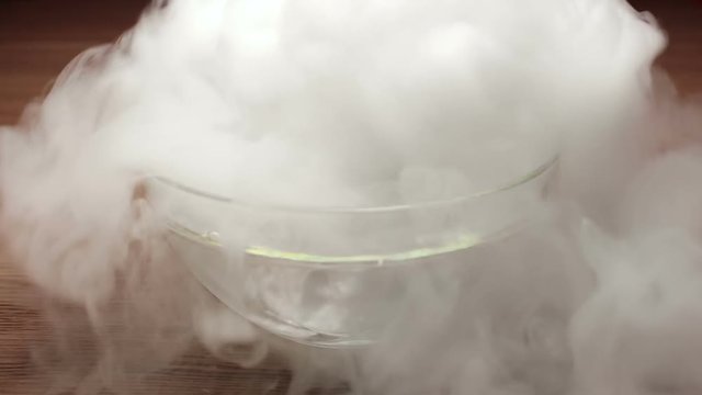 Putting big piece of dry ice into big plate with boiled water