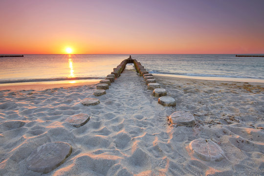 Fototapeta długie drewniane ostrogi na plaży, zachód słońca nad morzem