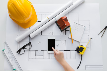 close up of hand with blueprint and smartphone