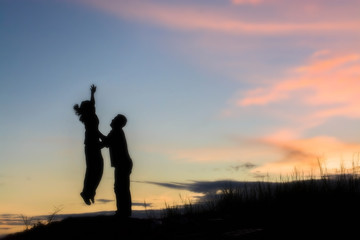 Obraz premium Young couple silhouette jumping sunset happy time