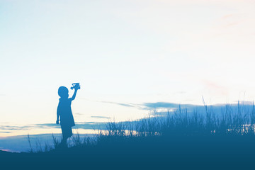 silhouette boy playing with toy airplane sunset