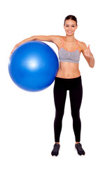 She's ready for a full body workout!  Portrait of an attractive and sporty young woman holding a pilates ball and thumb up to camera while stranding isolated.