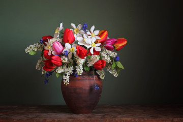 Still life with a spring bouquet in a clay jar.