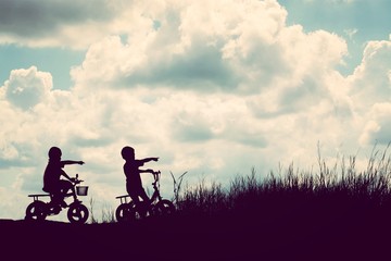 Obraz na płótnie Canvas two little boys bike silhouette