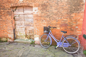 Fototapeta na wymiar old violet bicycle parked long an external wall in Burano island