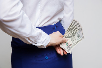 Unrecognizable businesswoman hiding dollars behind back