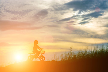 silhouette of little girl with little bike on the mountain