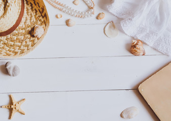 Hat, book and seashells on a wooden background. Top view